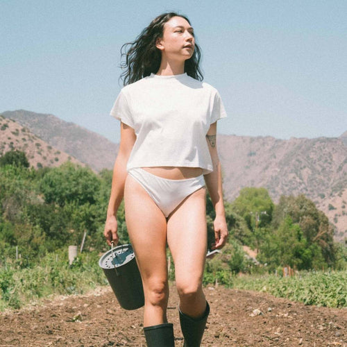 woman wearing organic cotton top and organic cotton bikini underwear in field
